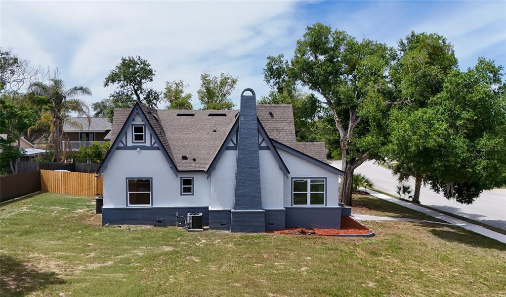 An exterior view of a white house with a gray brick chimney and dark trim — 1326 EAST AVENUE, CLERMONT, FL