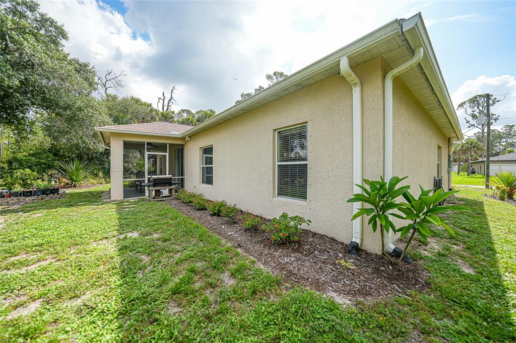 The exterior of a beige stucco house features a screened-in porch and a landscaped garden — 4481 BALSEY STREET, NORTH PORT, FL