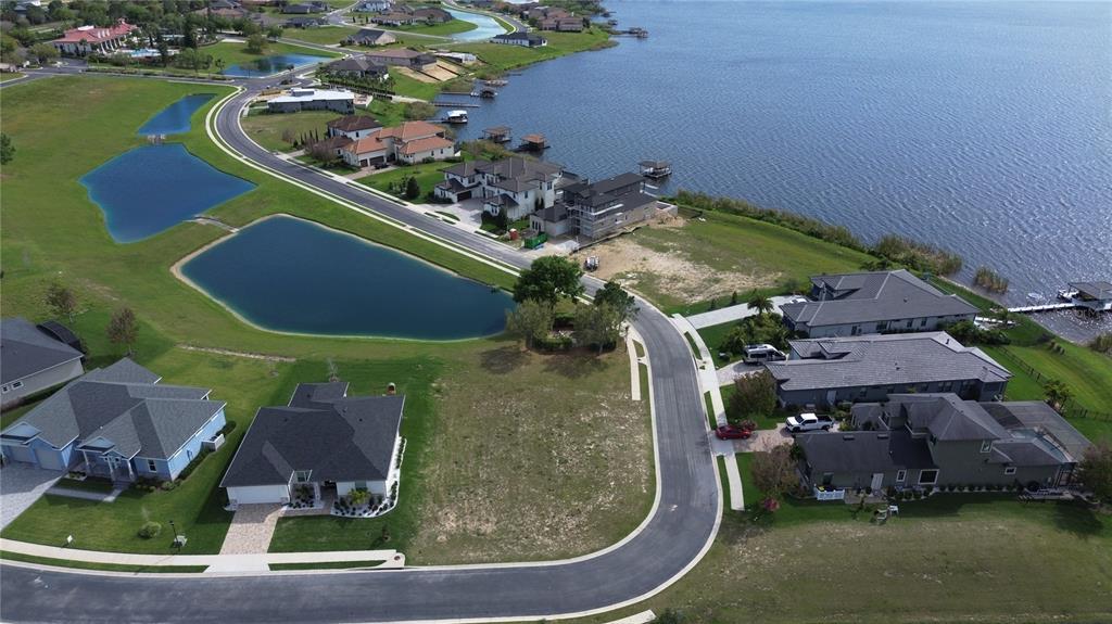 An aerial view shows a residential neighborhood with houses, a curved road, and several ponds — 760 WATER FERN TRAIL DRIVE, AUBURNDALE, FL