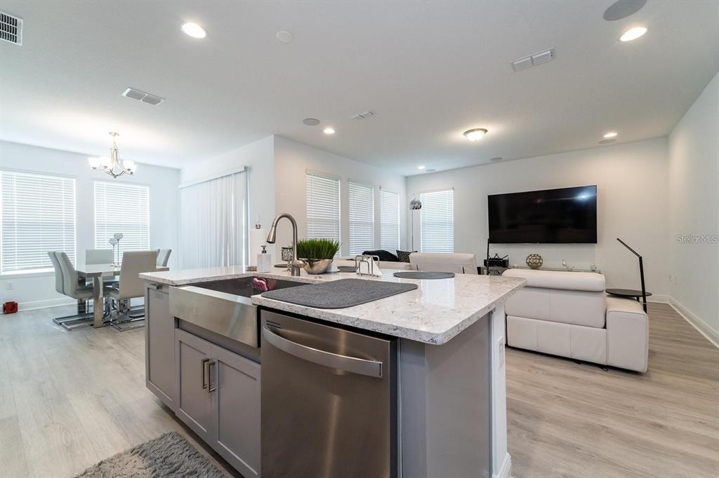 A kitchen island with a stainless steel sink and dishwasher faces a living room area — 9296 BOLERO ROAD, WINTER GARDEN, FL