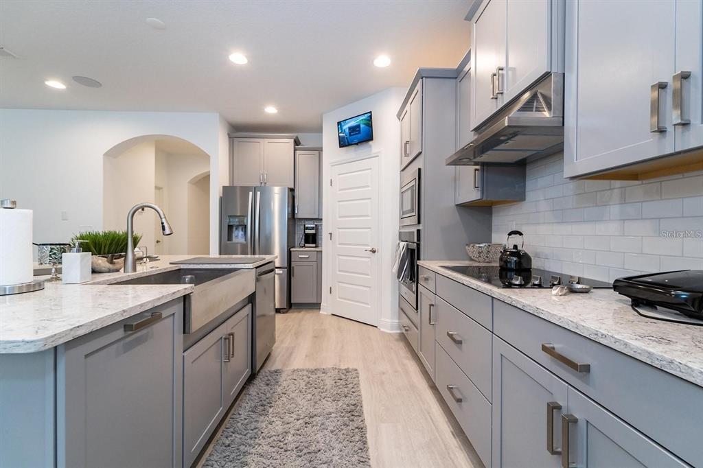 A modern kitchen features gray cabinets, white countertops, a farmhouse sink, and stainless steel appliances — 9296 BOLERO ROAD, WINTER GARDEN, FL
