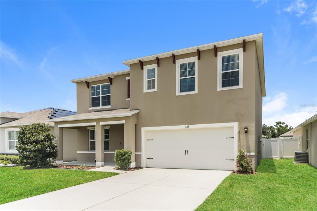 A two-story suburban house with a tan stucco exterior and a two-car garage — 321 ALEXZANDER WAY, WINTER HAVEN, FL