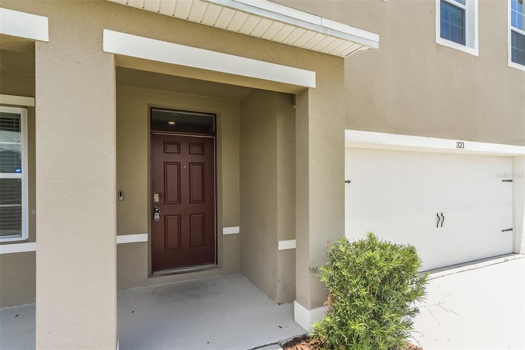 The exterior view shows a house entrance with a brown door and a white garage — 321 ALEXZANDER WAY, WINTER HAVEN, FL