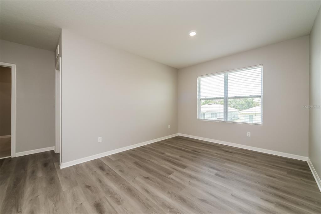 An empty bedroom features light gray walls, wood-look flooring, and a single window — 321 ALEXZANDER WAY, WINTER HAVEN, FL