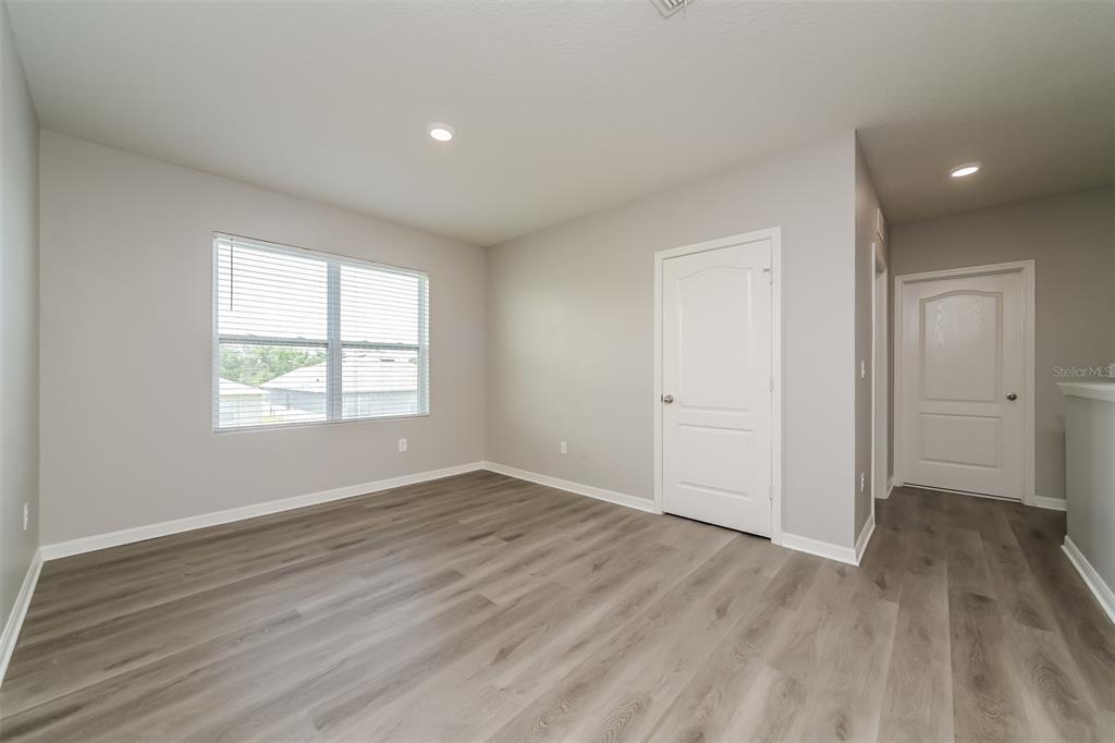 An empty room with light gray walls, wood-look flooring, and two white interior doors — 321 ALEXZANDER WAY, WINTER HAVEN, FL