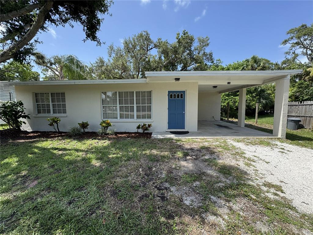 A single-story house with a blue front door, a carport, and a gravel driveway — 516 LAUREL ROAD W, NOKOMIS, FL
