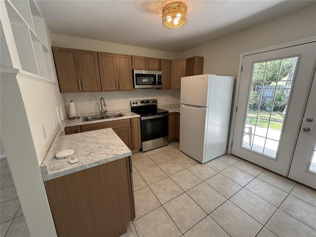 A kitchen features wood cabinets, marble-look countertops, stainless steel appliances, and a glass-paned door — 516 LAUREL ROAD W, NOKOMIS, FL