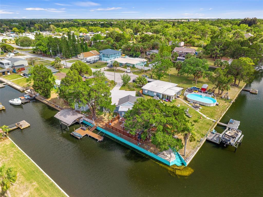 An aerial view shows a waterfront house with a pool, boat dock, and large trees — 7235 MARYLAND AVENUE, HUDSON, FL