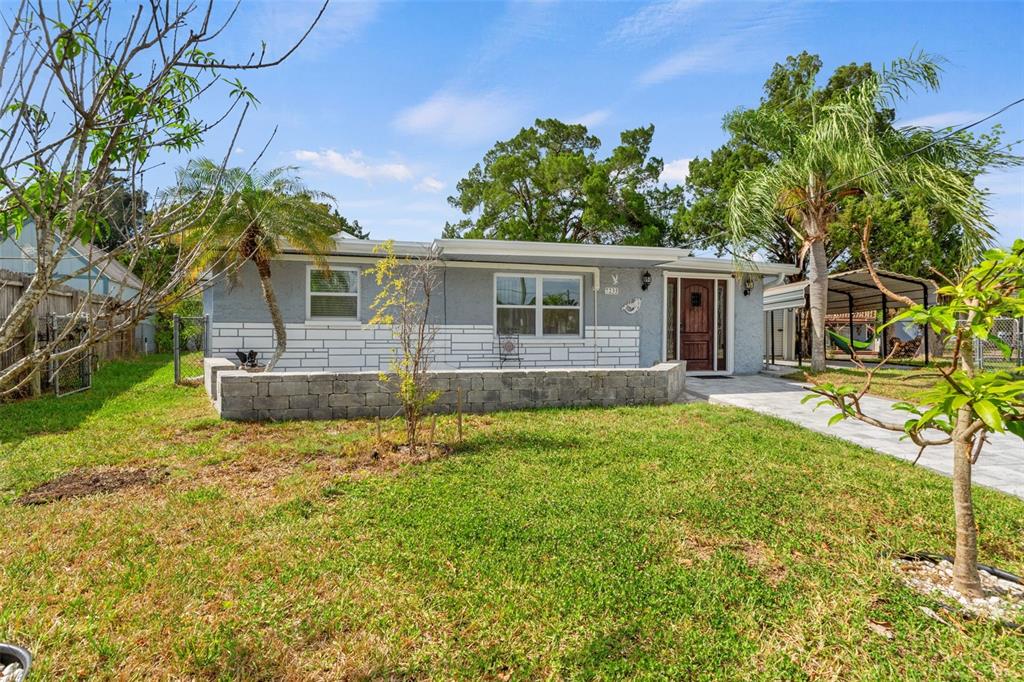 A single-story house with gray stucco, a stone facade, and a low retaining wall — 7235 MARYLAND AVENUE, HUDSON, FL