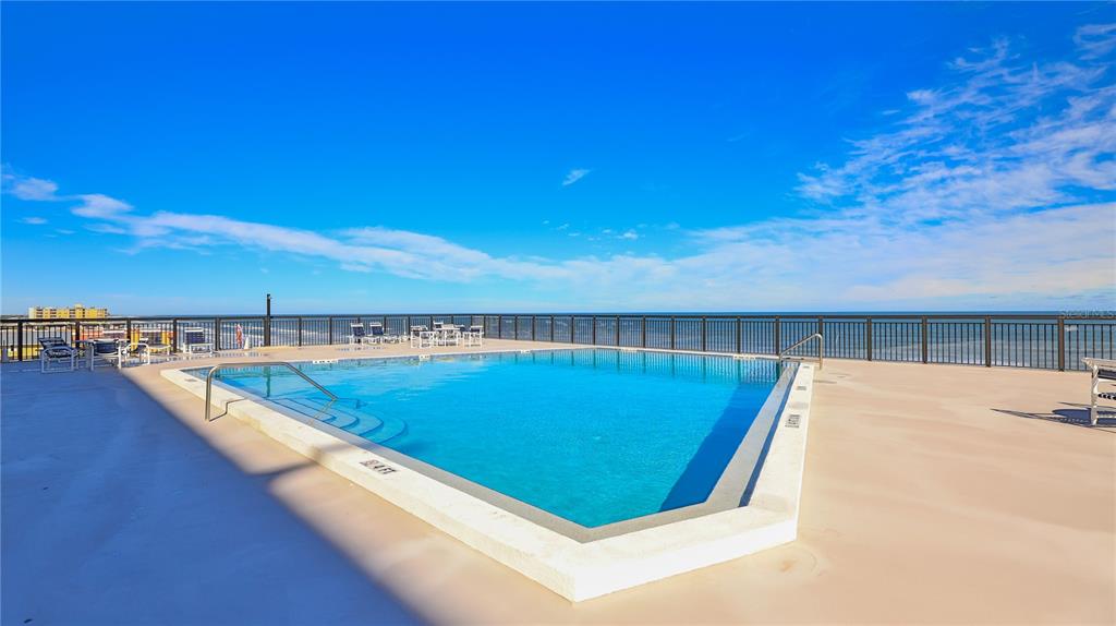 A rooftop swimming pool overlooks the ocean with a metal railing and lounge chairs nearby — 4139 ATLANTIC UNIT A406, NEW SMYRNA BEACH, FL