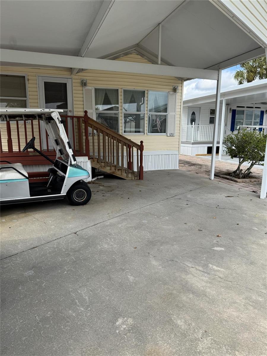 A yellow mobile home features a wooden staircase, a carport, and a parked golf cart — 5251 SE 67th Avenue, Okeechobee FL 34974, OKEECHOBEE, FL