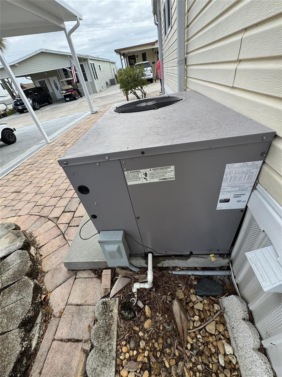 An outdoor air conditioning unit sits on a concrete pad next to a residential building — 5251 SE 67th Avenue, Okeechobee FL 34974, OKEECHOBEE, FL