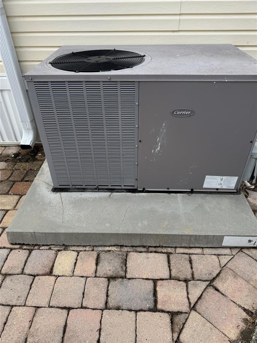 A gray Carrier air conditioning unit sits on a concrete pad outdoors — 5251 SE 67th Avenue, Okeechobee FL 34974, OKEECHOBEE, FL