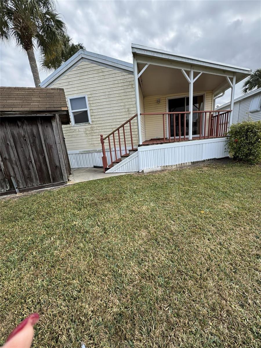 Exterior view of a light-colored mobile home with a wooden deck and adjacent shed — 5251 SE 67th Avenue, Okeechobee FL 34974, OKEECHOBEE, FL