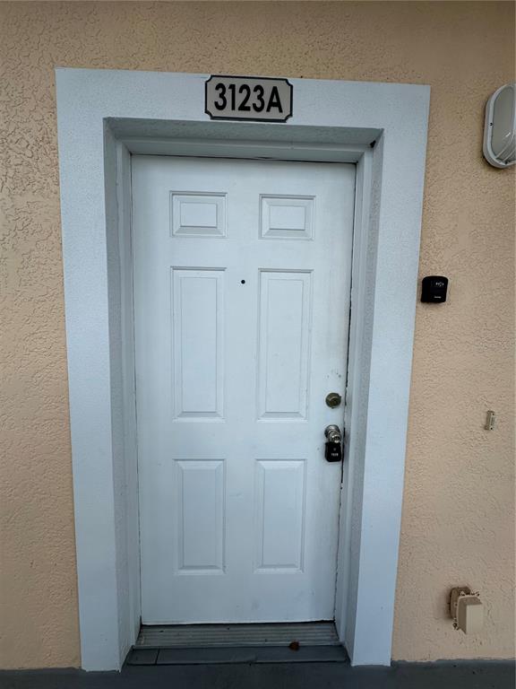 A white front door with a lockbox and a unit number sign above the frame — 3123 SUN LAKE COURT UNIT A, KISSIMMEE, FL