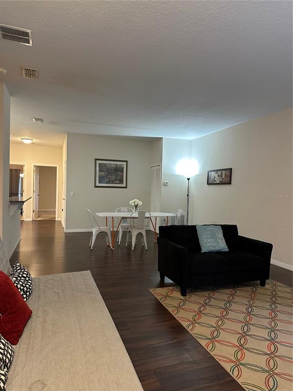 A living room and dining area feature dark wood flooring and a black sofa — 3123 SUN LAKE COURT UNIT A, KISSIMMEE, FL