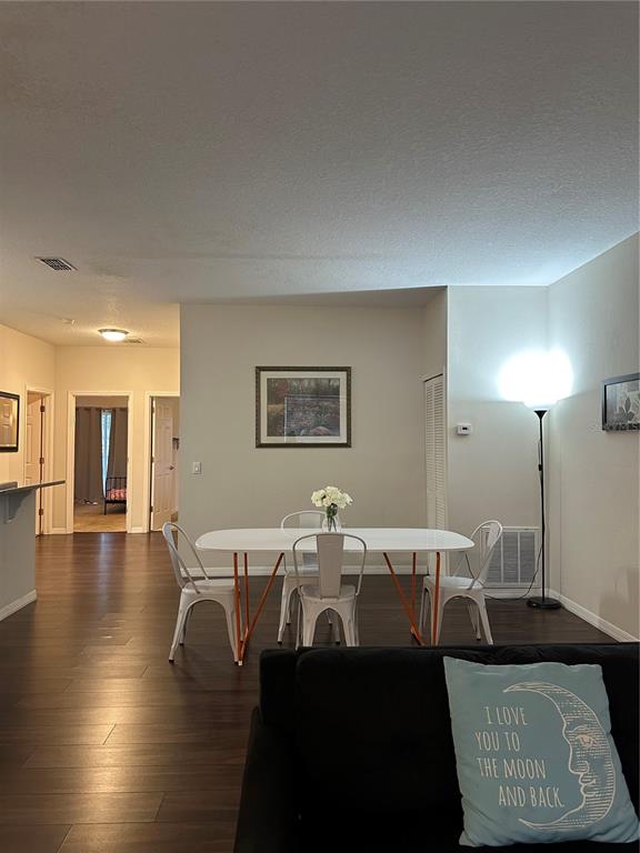 A dining area with a white table and metal chairs sits before a living room — 3123 SUN LAKE COURT UNIT A, KISSIMMEE, FL