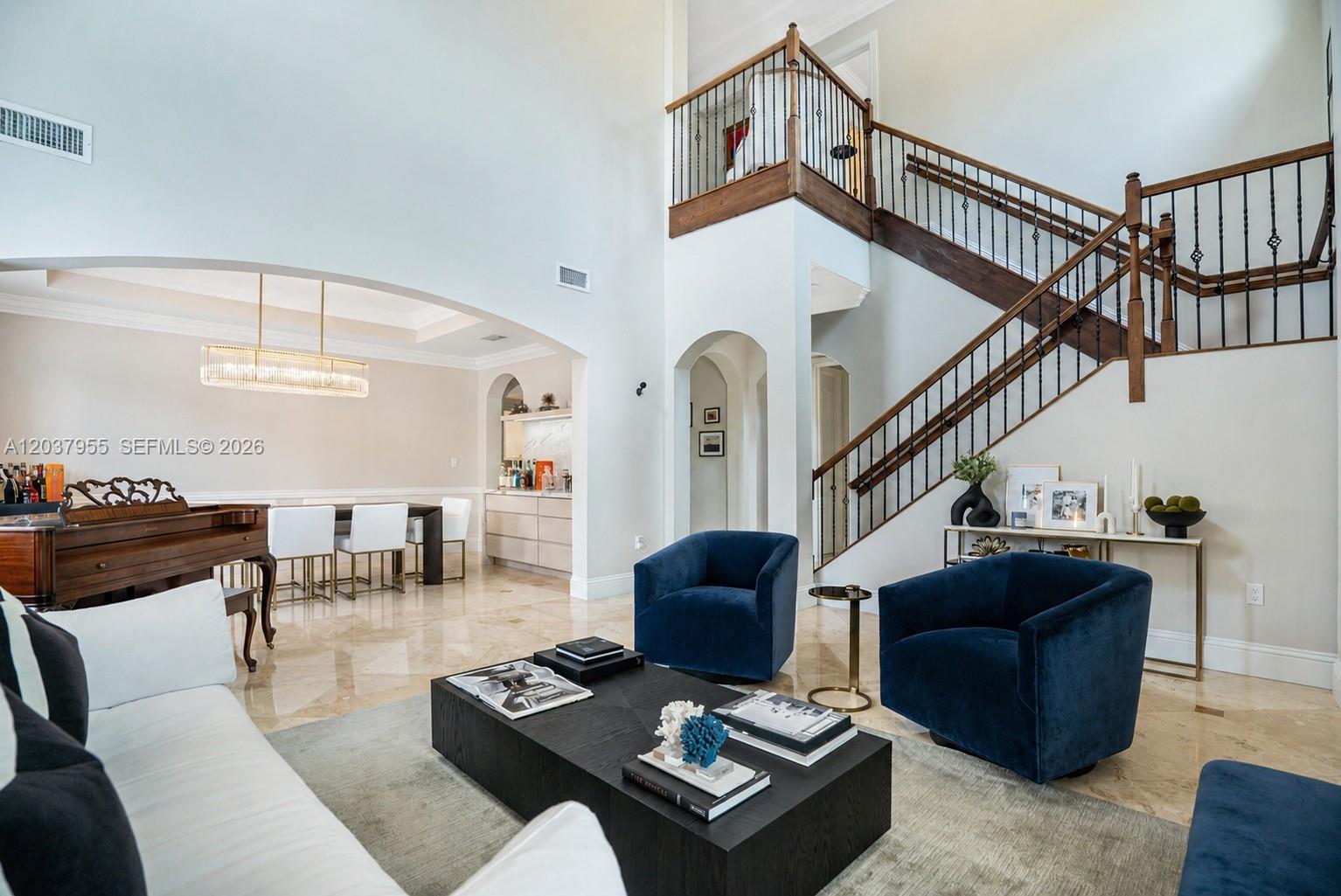 A living room features a grand staircase, blue velvet armchairs, and a black coffee table — 8919 NE 10th Ave, Miami FL 33138, MIAMI, FL