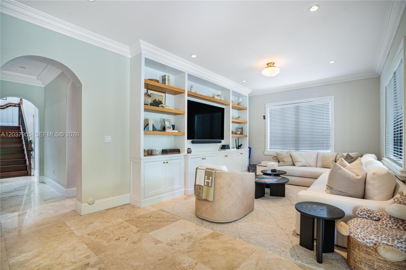 A living room features a built-in media unit, light tile flooring, and an arched entryway — 8919 NE 10th Ave, Miami FL 33138, MIAMI, FL