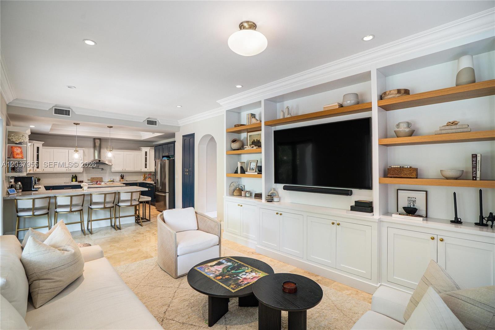 A living room with built-in shelving, a television, and an open kitchen with bar seating — 8919 NE 10th Ave, Miami FL 33138, MIAMI, FL