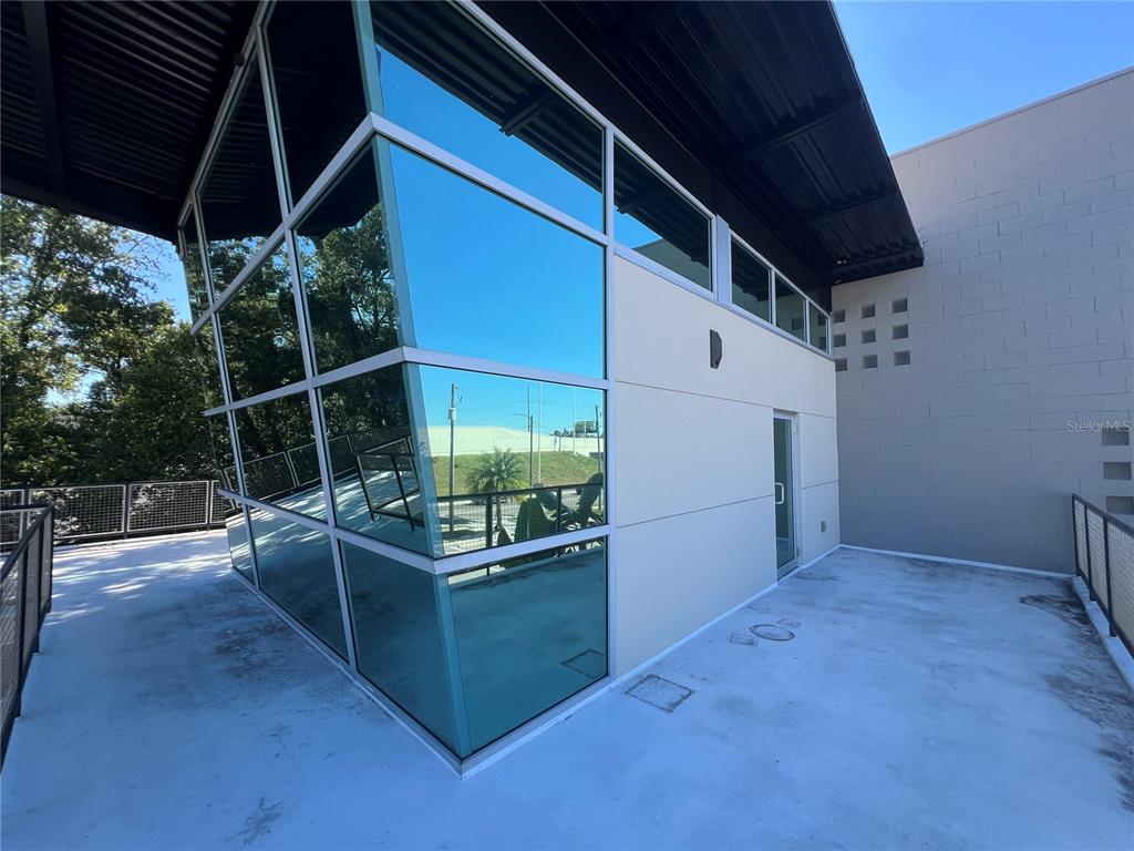A modern rooftop terrace features a glass-walled structure and a concrete deck with railings — 4007 N TALIAFERRO AVENUE UNIT B-C-D, TAMPA, FL