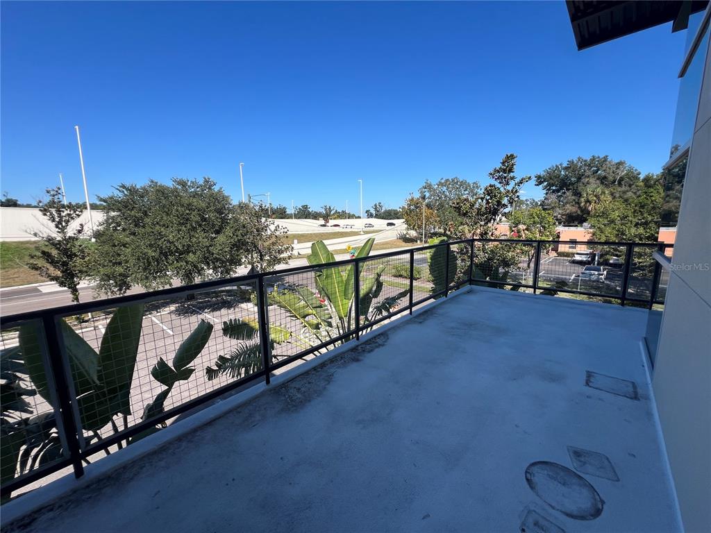 A balcony with a metal railing overlooks a parking lot and a highway overpass — 4007 N TALIAFERRO AVENUE UNIT B-C-D, TAMPA, FL