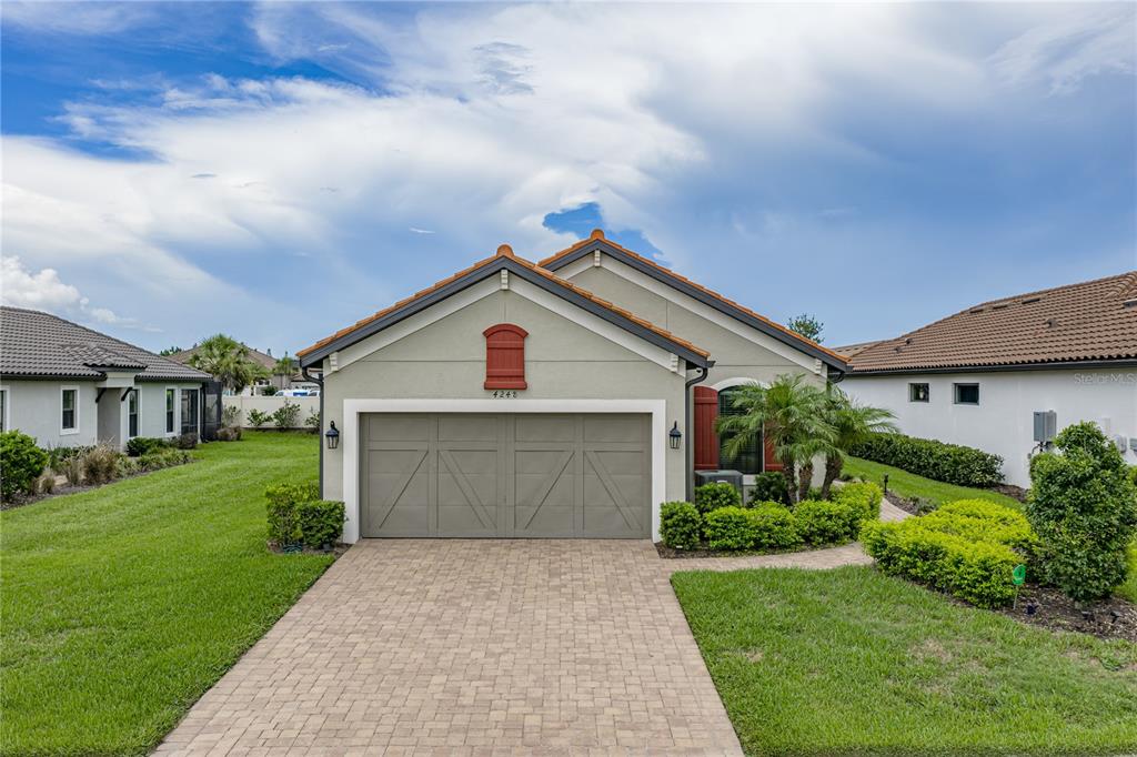 A single-story house with a beige stucco exterior, a two-car garage, and a paved driveway — 4248 CAIROLI COURT, WESLEY CHAPEL, FL