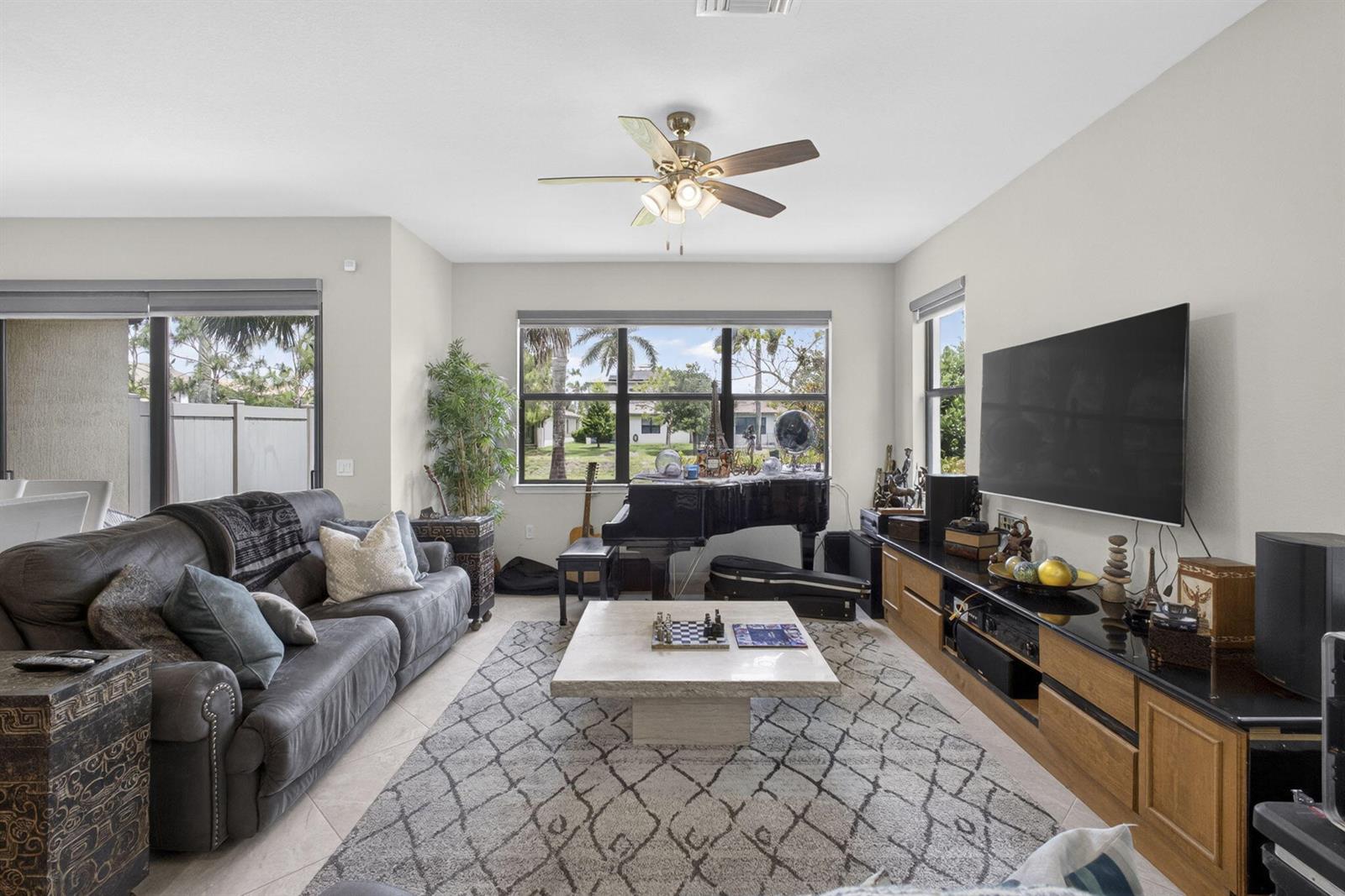 A living room features a grand piano, a large television, and a stone coffee table — 8347 Cadre Noir Road, Lake Worth FL 33467, LAKE WORTH, FL