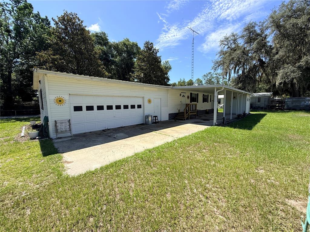A white single-story house with a garage, a concrete driveway, and a covered carport — 2828 NE 147TH TERRACE, SILVER SPRINGS, FL