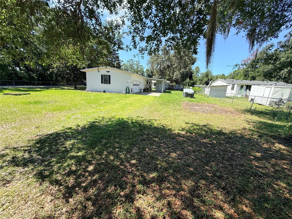 A single-story house sits on a grassy lot behind a chain-link fence — 2828 NE 147TH TERRACE, SILVER SPRINGS, FL