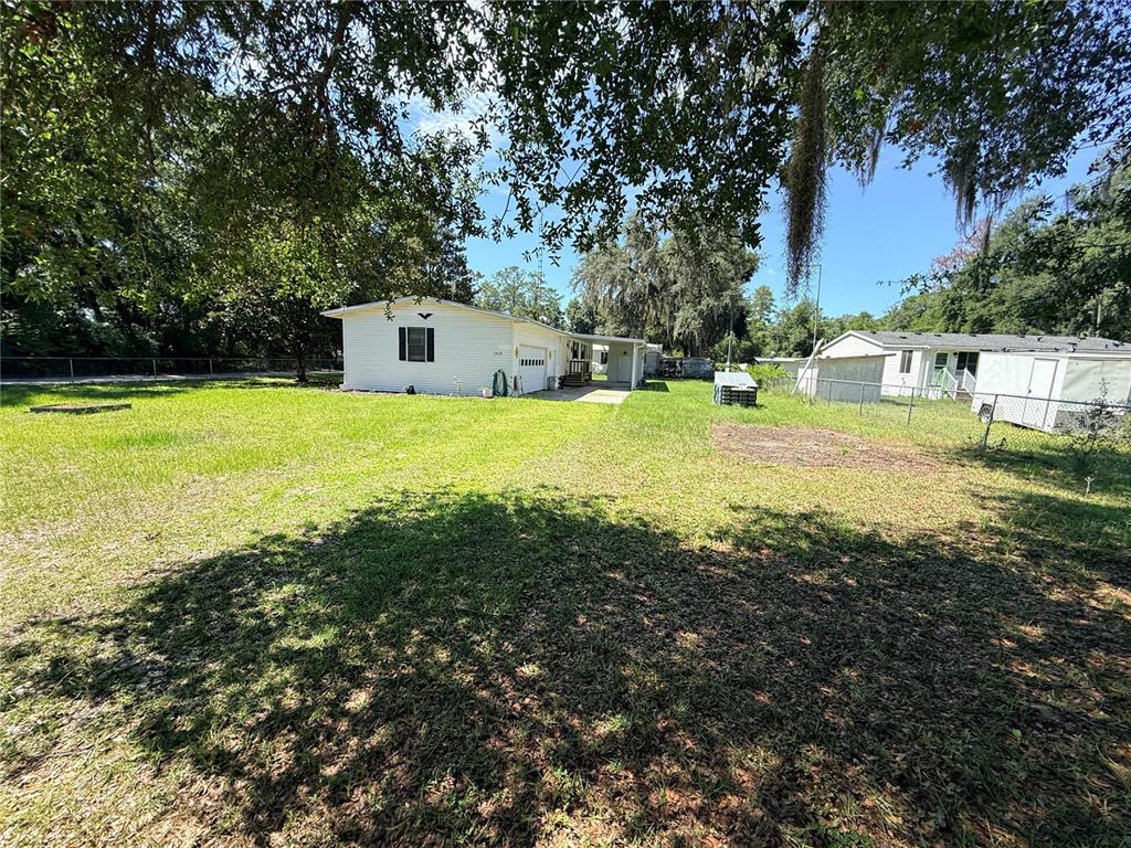A white single-story house with a carport sits on a large, grassy lot — 2828 NE 147TH TERRACE, SILVER SPRINGS, FL