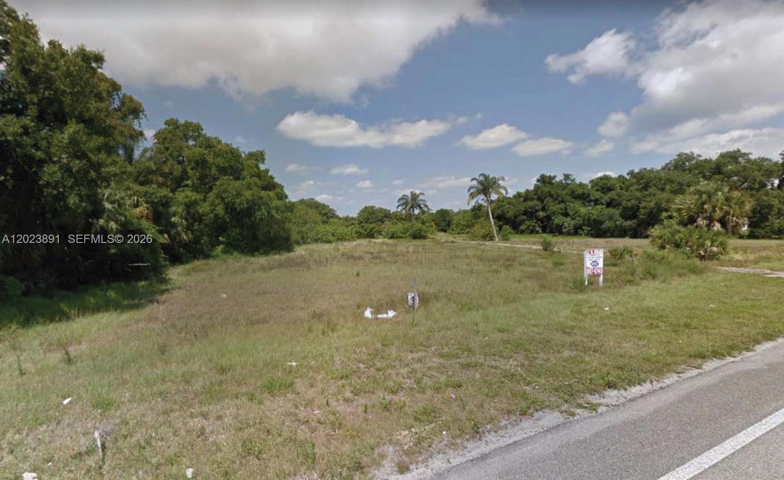 A vacant, grassy lot with scattered trees and a real estate sign along a road — 7985 US Highway 1, Vero Beach FL 32967, VERO BEACH, FL