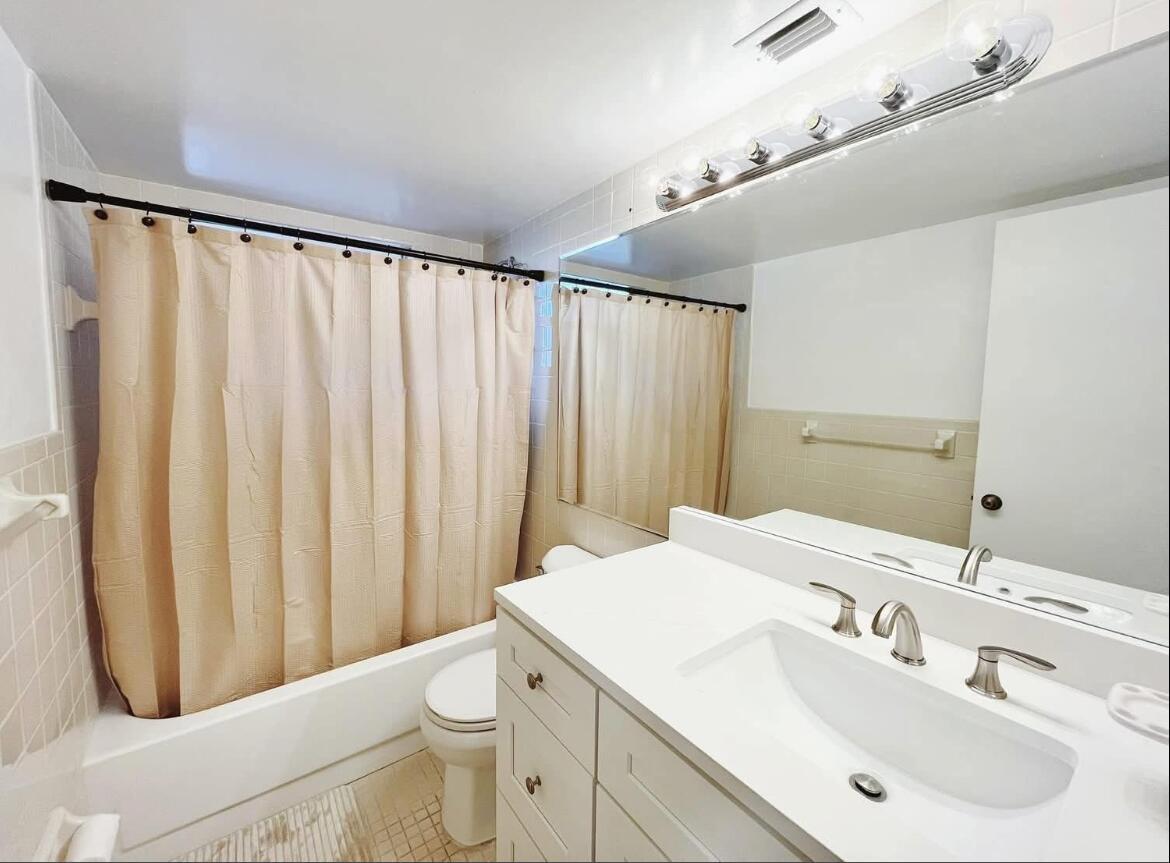 A living room features beige tile flooring, a sectional sofa, a wall clock, and a pass-through window — 7080 Nova Drive # 307b, Davie FL 33317, DAVIE, FL