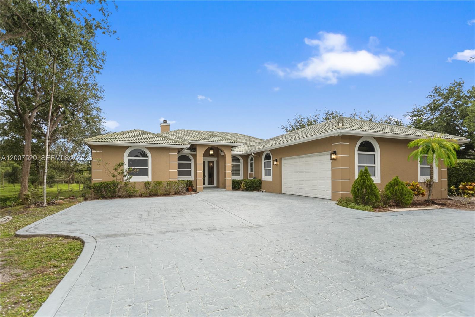 A tan single-story house with a tiled roof and a large stamped concrete driveway — 12343 NW 19th St, Plantation FL 33323, PLANTATION, FL