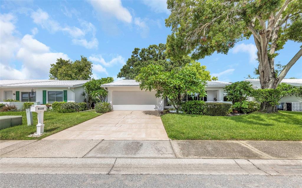 A single-story house with a white exterior, a two-car garage, and a concrete driveway — 9110 40TH WAY N, PINELLAS PARK, FL