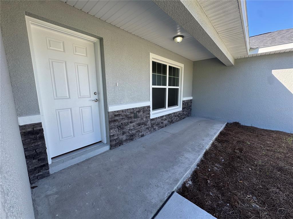 A kitchen features white cabinets, stainless steel appliances, and a stone countertop with a sink — 8781 N QUARRY DRIVE, CITRUS SPRINGS, FL