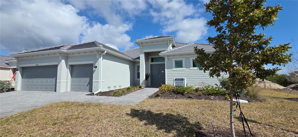 A single-story house with a gray exterior, a three-car garage, and a paved walkway — 8006 LAKES EDGE LANE, PORT CHARLOTTE, FL