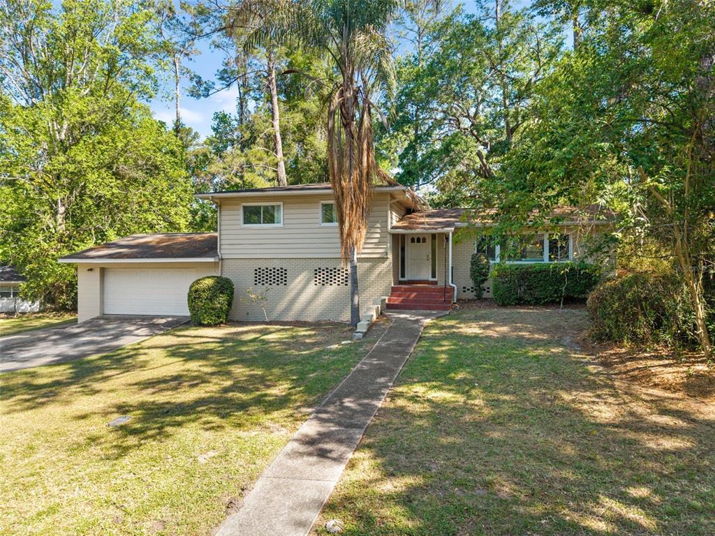 A two-story split-level house with a beige brick and siding exterior and a palm tree — 2910 SW 1ST AVENUE, GAINESVILLE, FL
