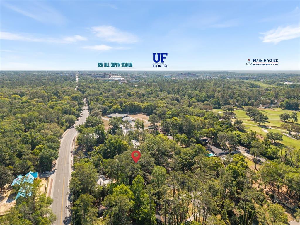 An aerial view shows a wooded residential lot marked with a red pin near campus — 2910 SW 1ST AVENUE, GAINESVILLE, FL