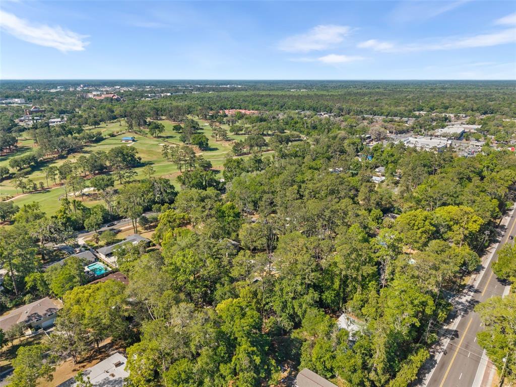 An aerial view shows a residential neighborhood with dense trees, a golf course, and roads — 2910 SW 1ST AVENUE, GAINESVILLE, FL