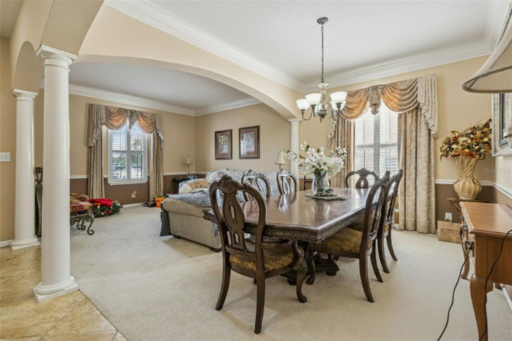 A dining room with a wooden table and chairs sits adjacent to a carpeted living area — 3676 BRIAR RUN DRIVE, CLERMONT, FL