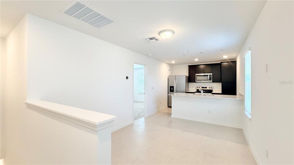 A kitchen with dark cabinets and a breakfast bar overlooks an open tiled dining area — 5694 ENCHANTED MEADOW ALLEY UNIT B, CLERMONT, FL