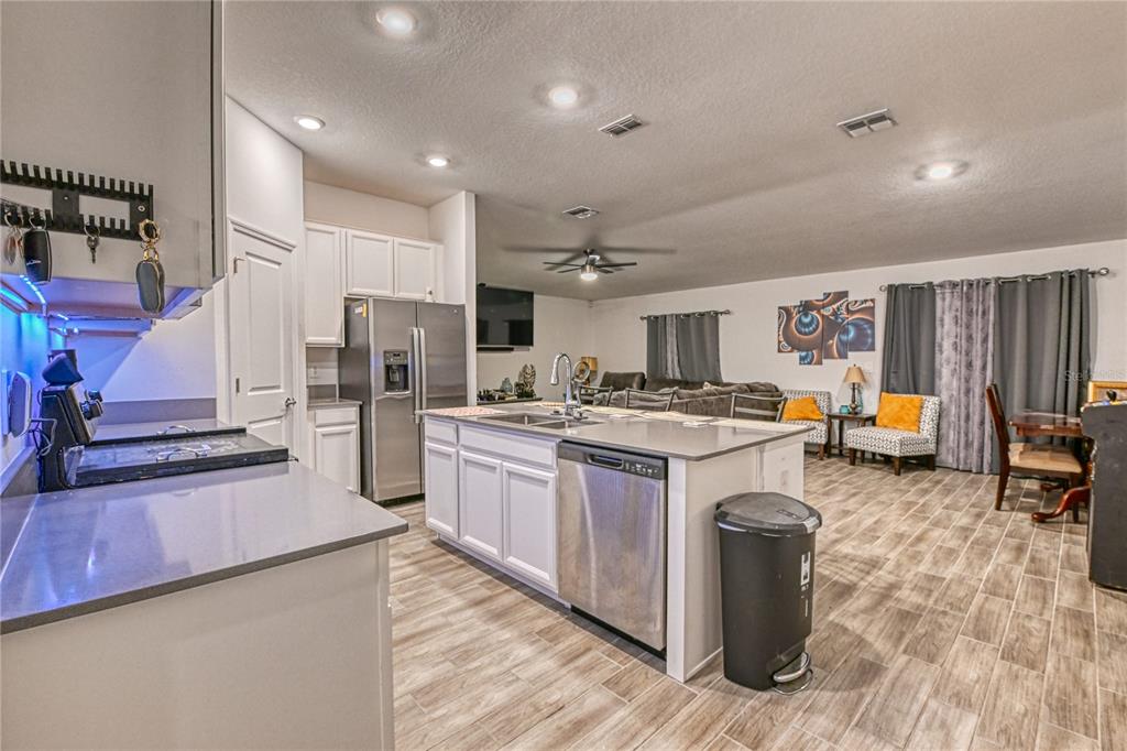 A kitchen with white cabinets, stainless steel appliances, and a central island overlooks a living area — 1159 POMELO STREET, DAVENPORT, FL