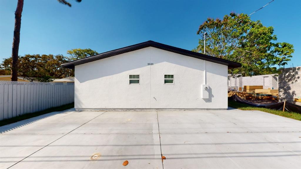 The exterior of a white, single-story building features a concrete driveway and two small windows — 5022 10TH AVENUE N, ST PETERSBURG, FL
