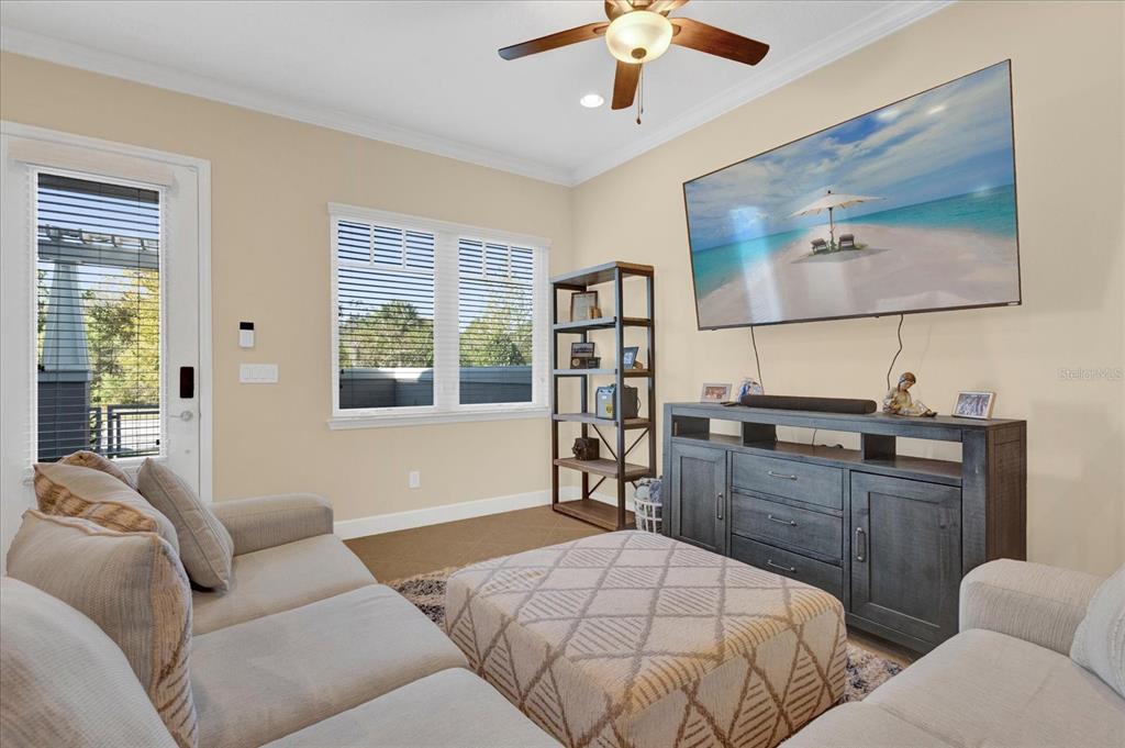 A living room features a sectional sofa, a large television, and a wooden media console — 9219 LAUREATE BOULEVARD, ORLANDO, FL