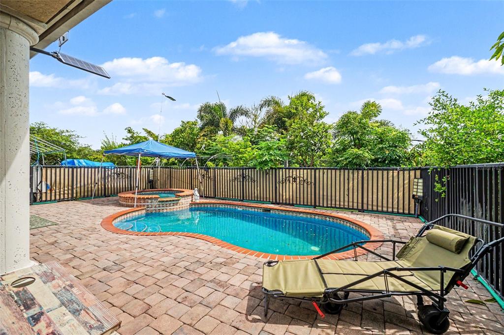 A backyard features a swimming pool, a hot tub, a lounge chair, and a fence — 20831 COPPERHEAD DRIVE, LEHIGH ACRES, FL
