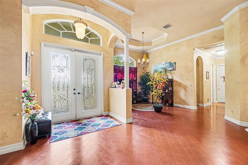 A spacious foyer features hardwood floors, a double-door entrance, and warm-toned textured walls — 20831 COPPERHEAD DRIVE, LEHIGH ACRES, FL