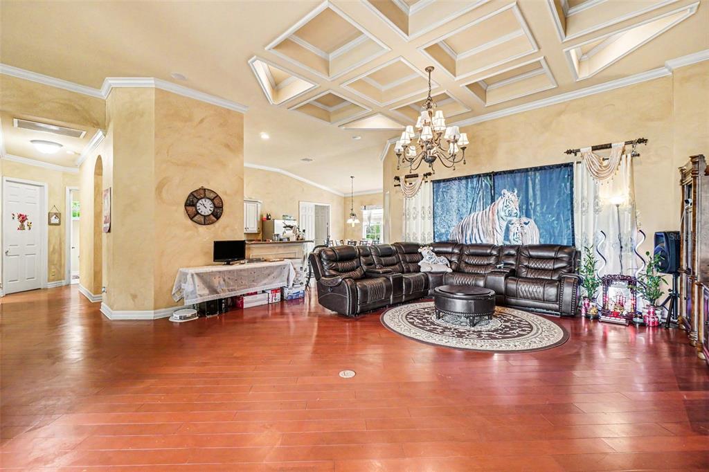 A spacious living room features a coffered ceiling, hardwood floors, and a large leather sectional — 20831 COPPERHEAD DRIVE, LEHIGH ACRES, FL