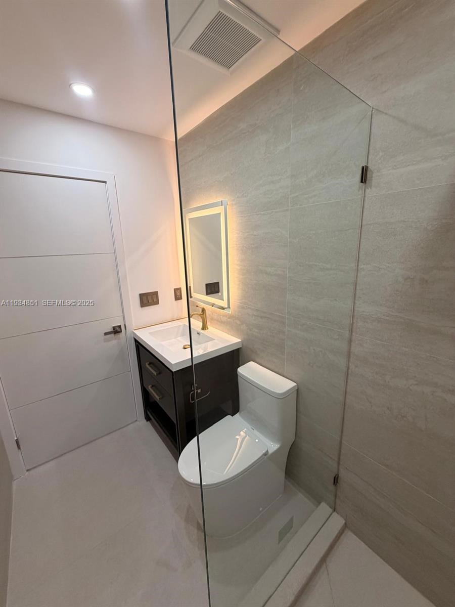 A modern bathroom features a glass-enclosed shower, a dark wood vanity, and a toilet — 2436 SW 7th St # 4, Miami FL 33135, MIAMI, FL