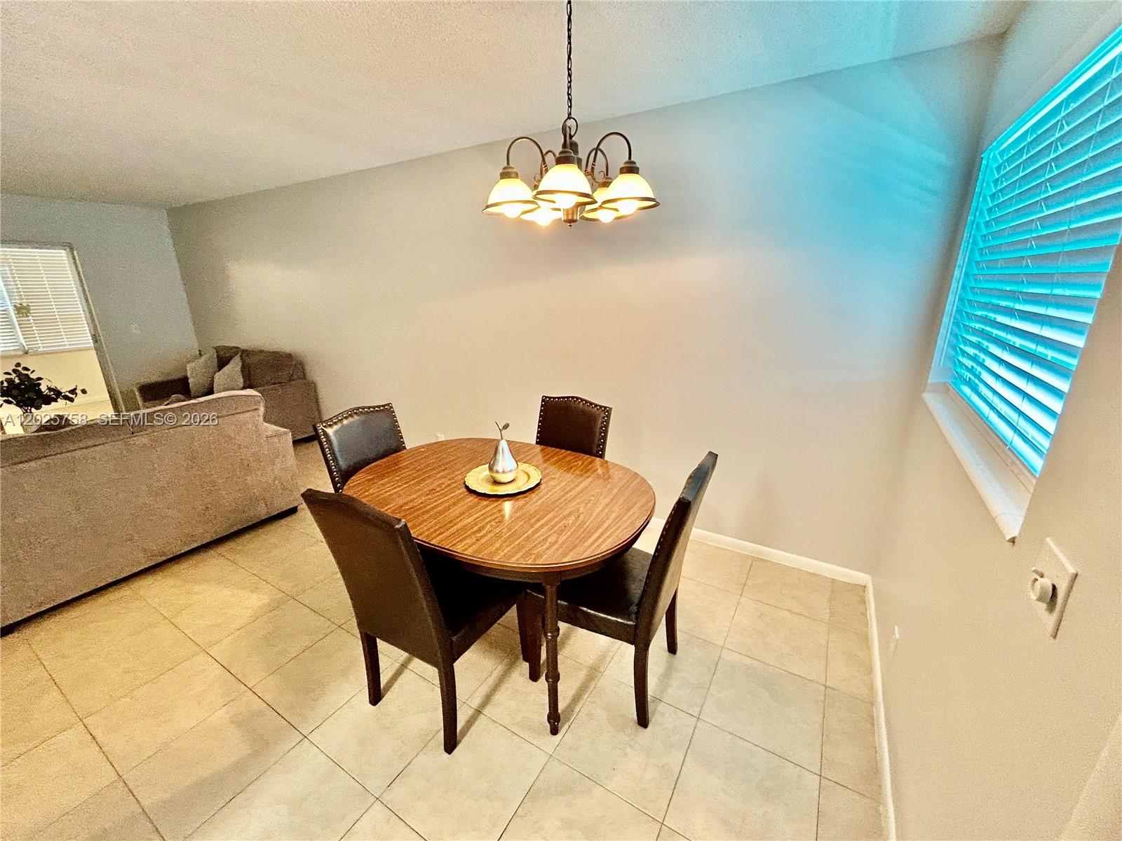 A dining area features a wooden table with four chairs under a hanging light fixture — 2213 NE 1st Ct # 203, Boynton Beach FL 33435, BOYNTON BEACH, FL